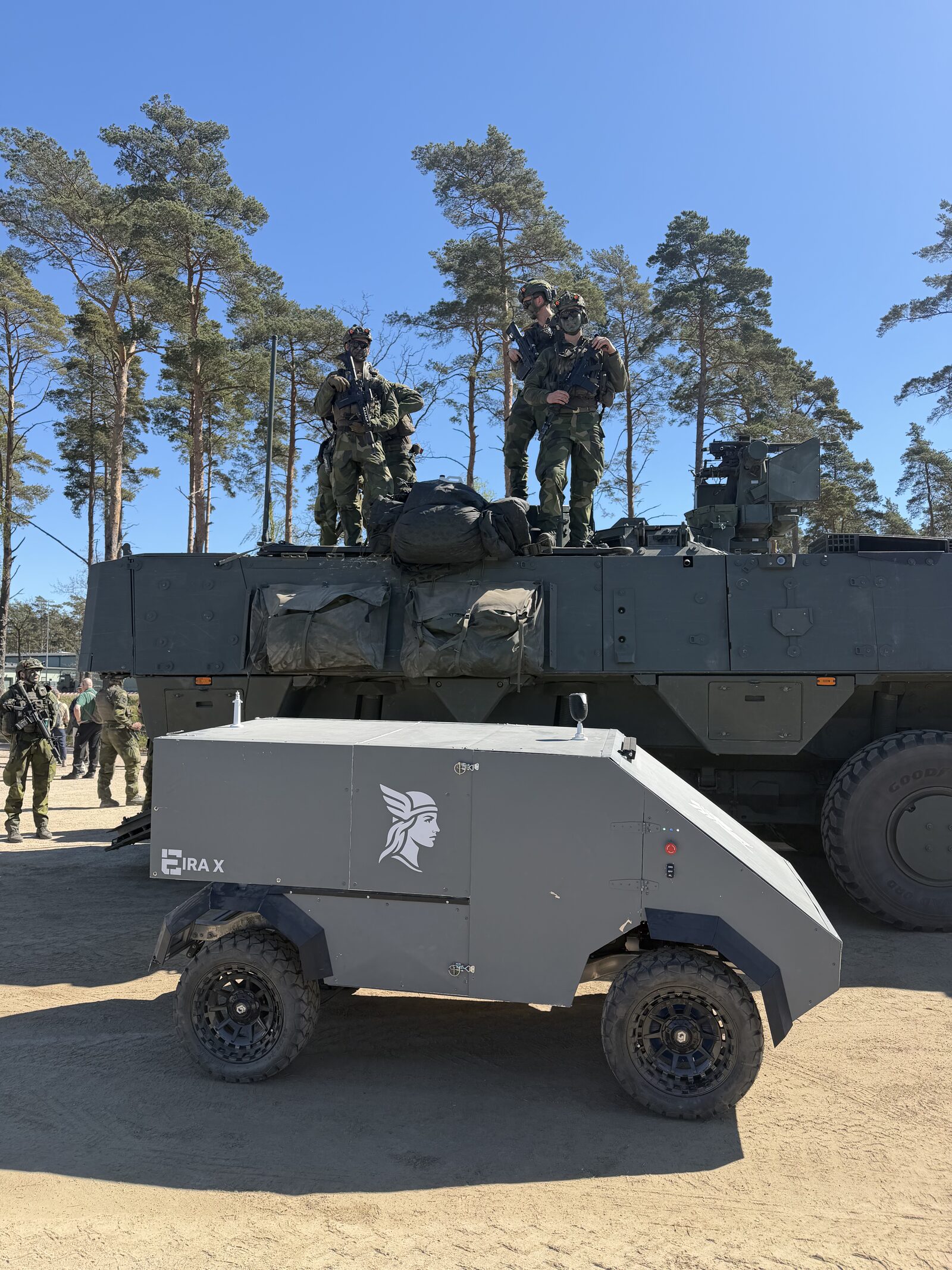 Eira X side profile with soldiers on a CV90 in the background.
