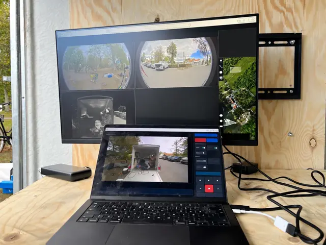 Operator station: laptop console with live camera views, arm and E-stop, beside a second monitor